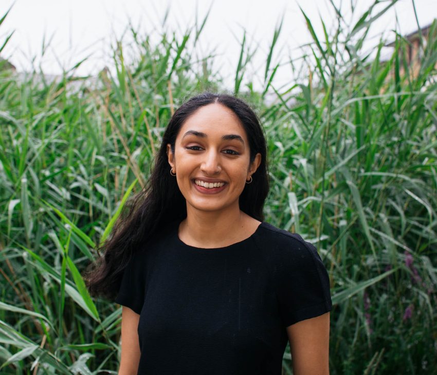 Woman in black dress standing in front of long grass
