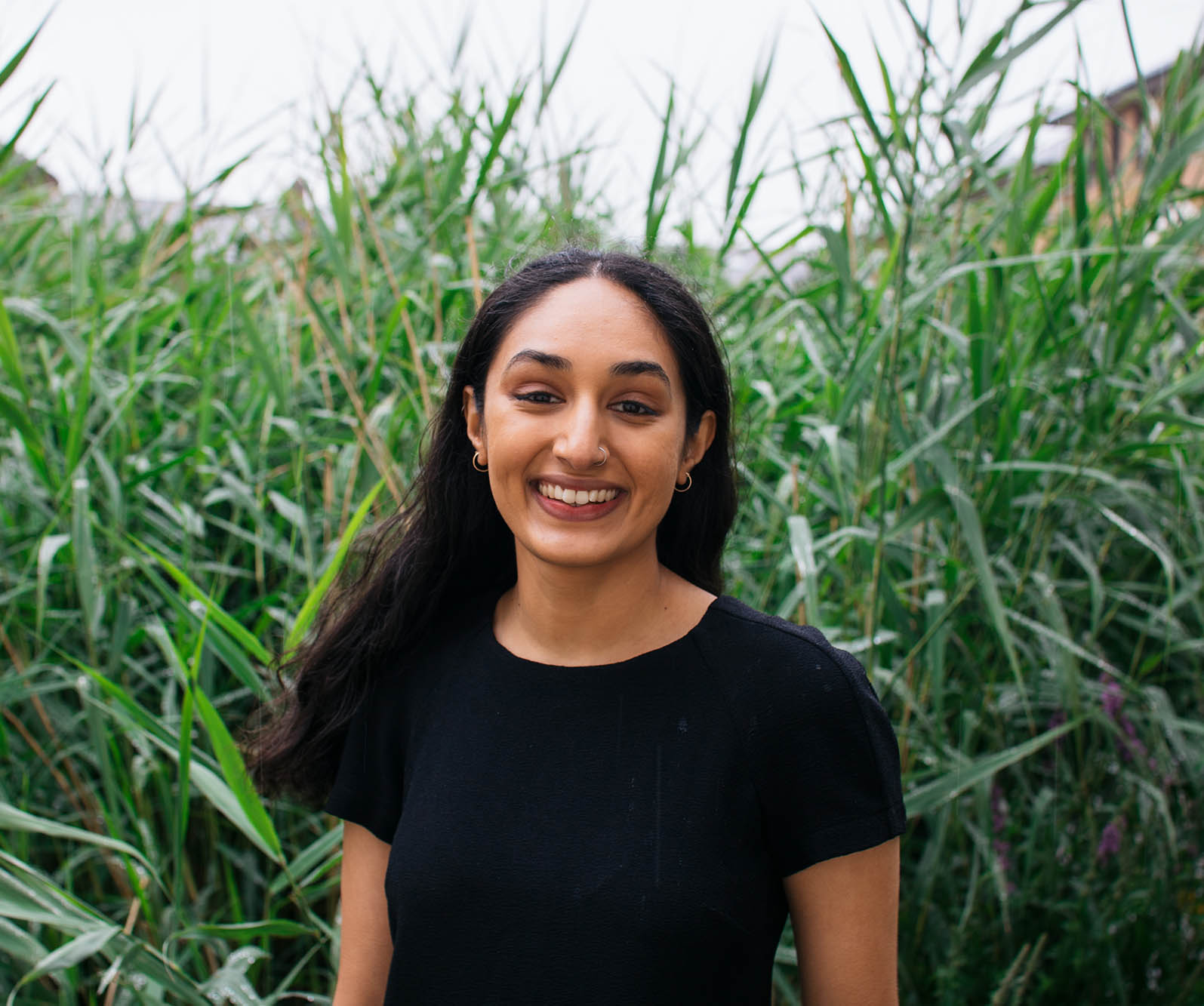 Woman in black dress standing in front of long grass
