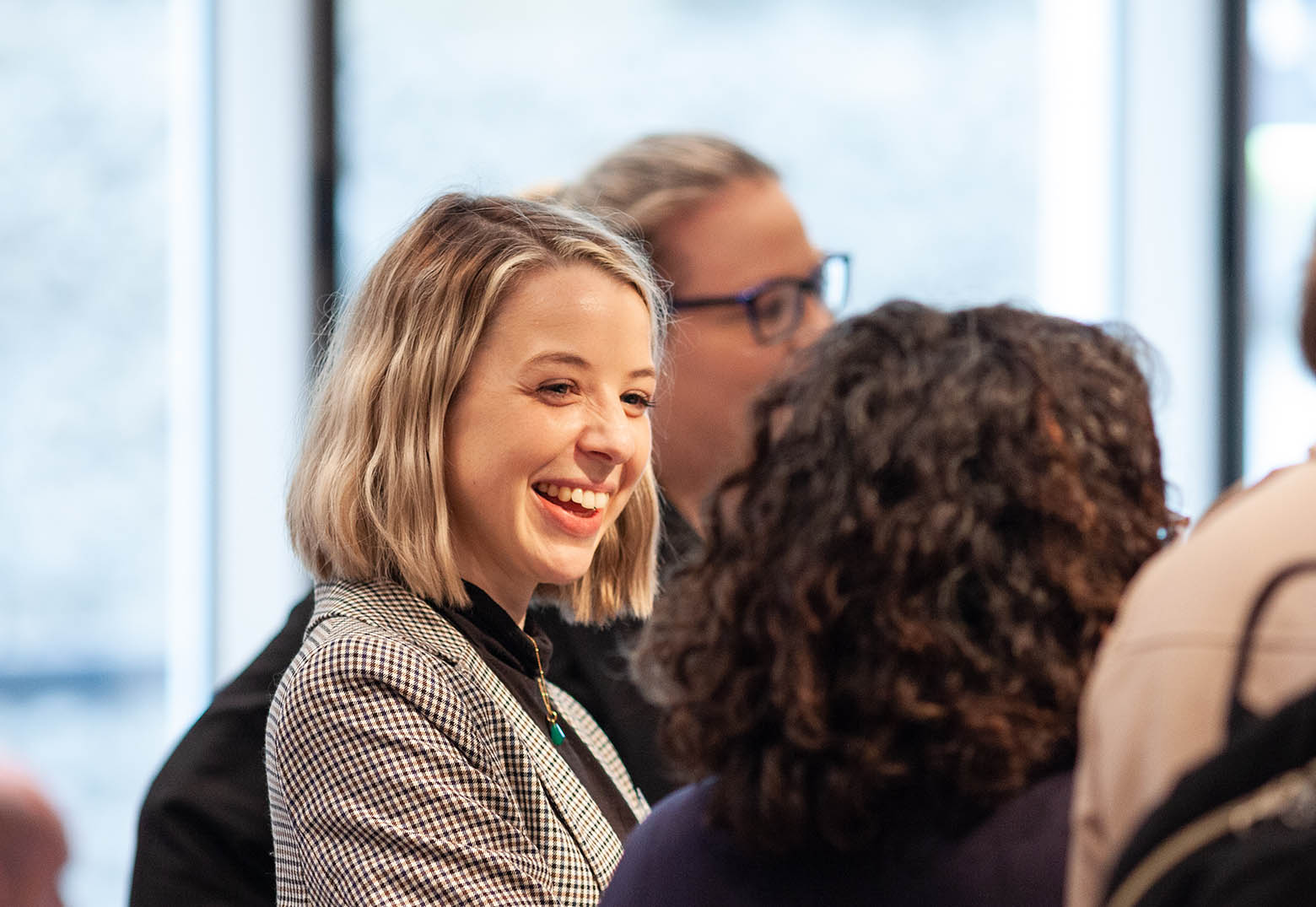 woman in blazer speaking and laughing with another woman at an event.