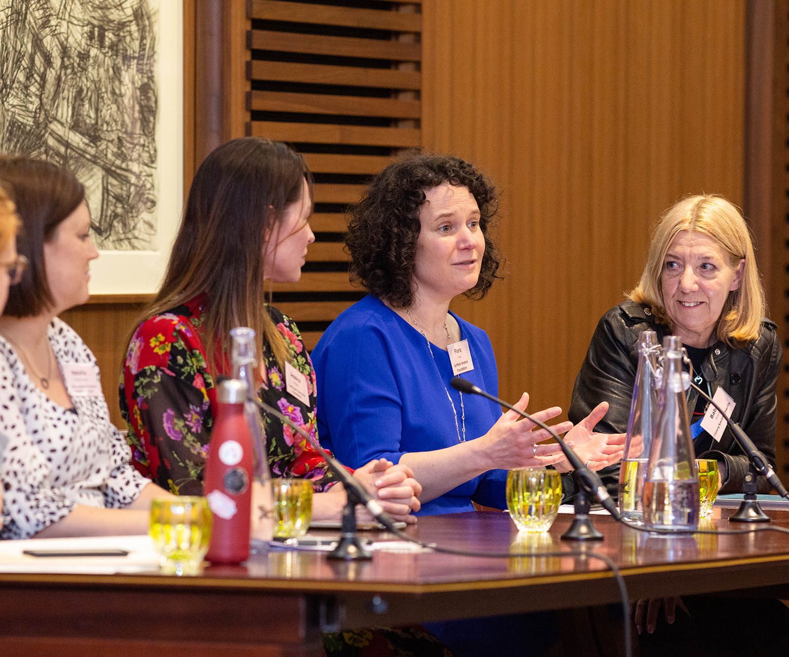 a woman in a blue dress speaking on a panel