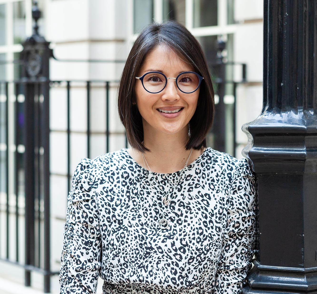 woman in glasses leaning on lampost