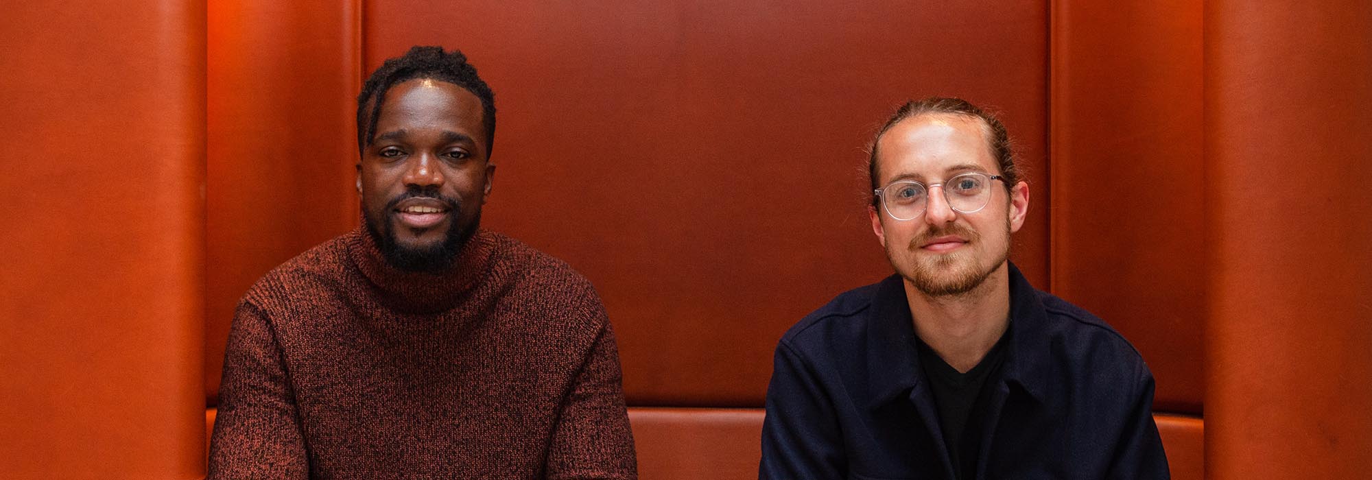 two men sitting on a leather chair