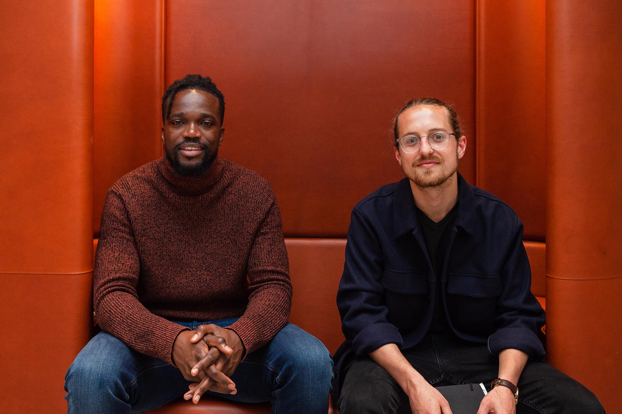 two men sitting on a leather sofa