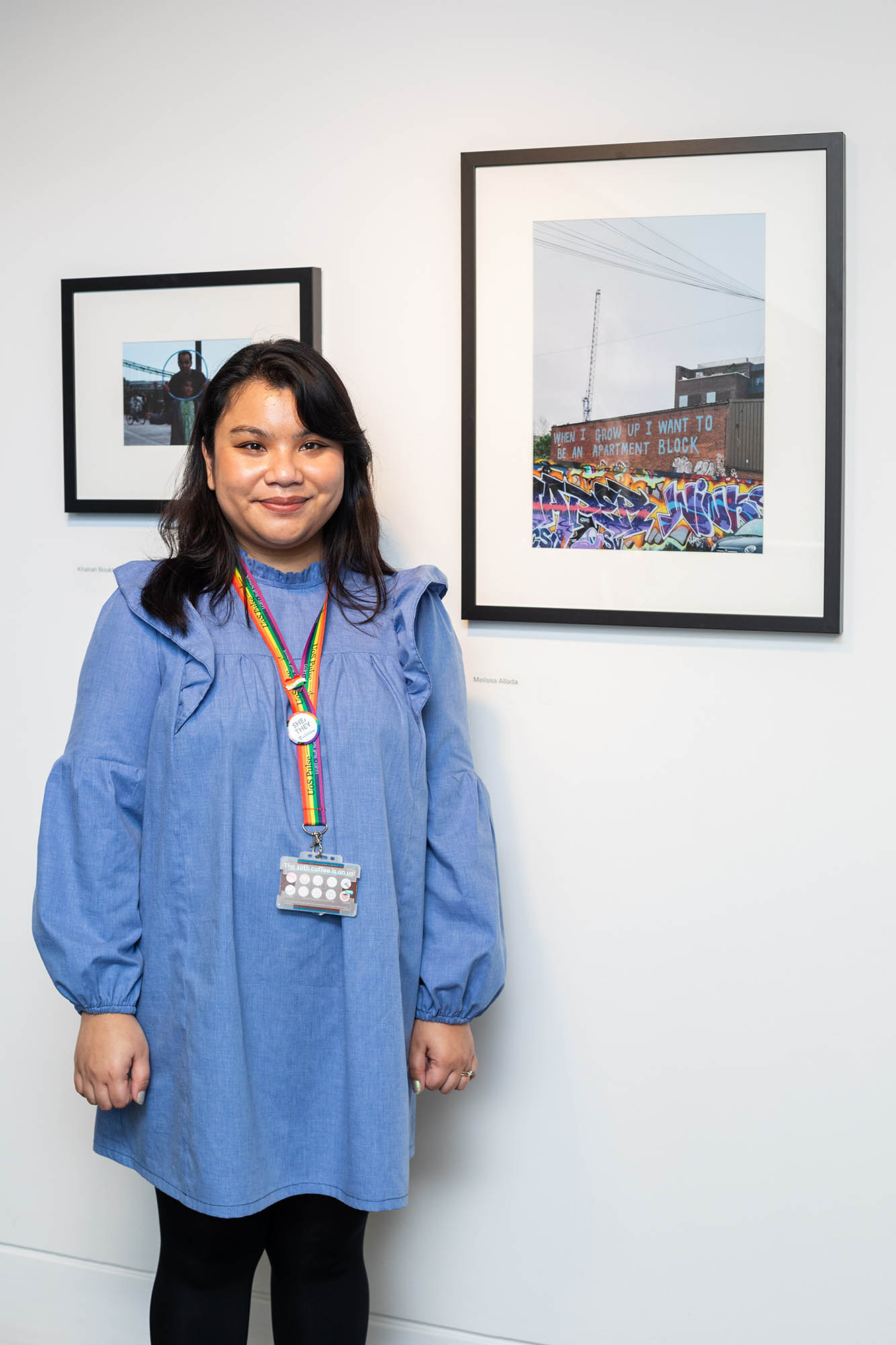 woman standing next to framed pictures in a gallery
