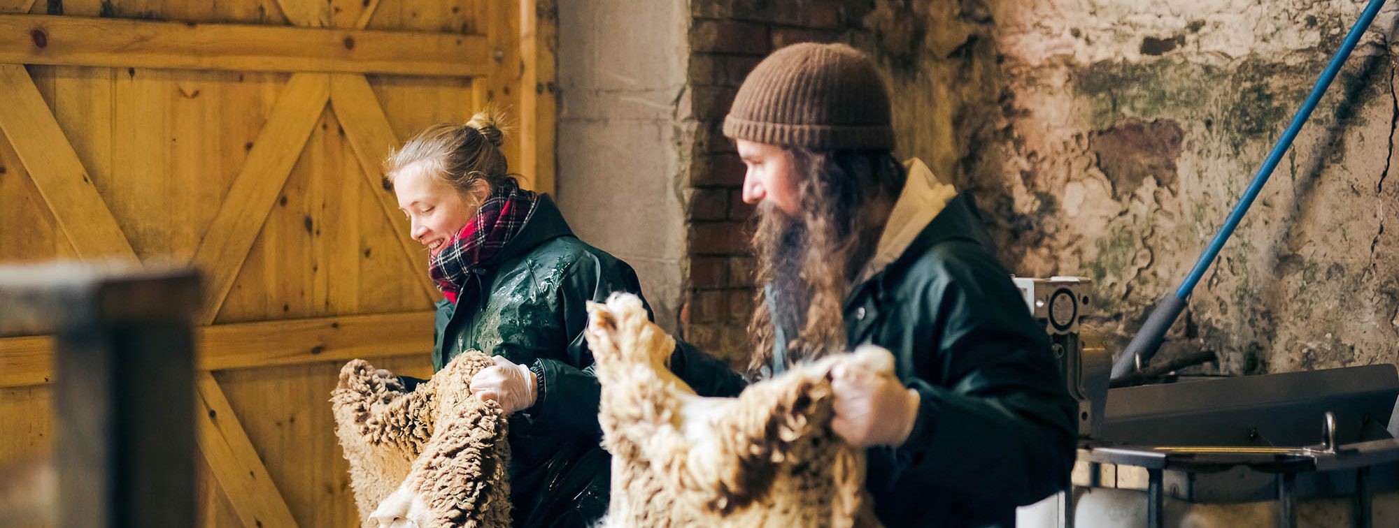 a woman and a man in a tannery holding hides