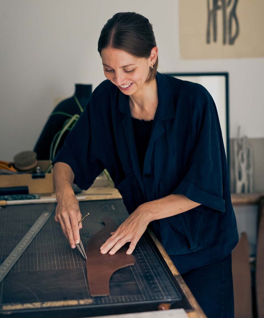 a woman cutting leather in a workshop