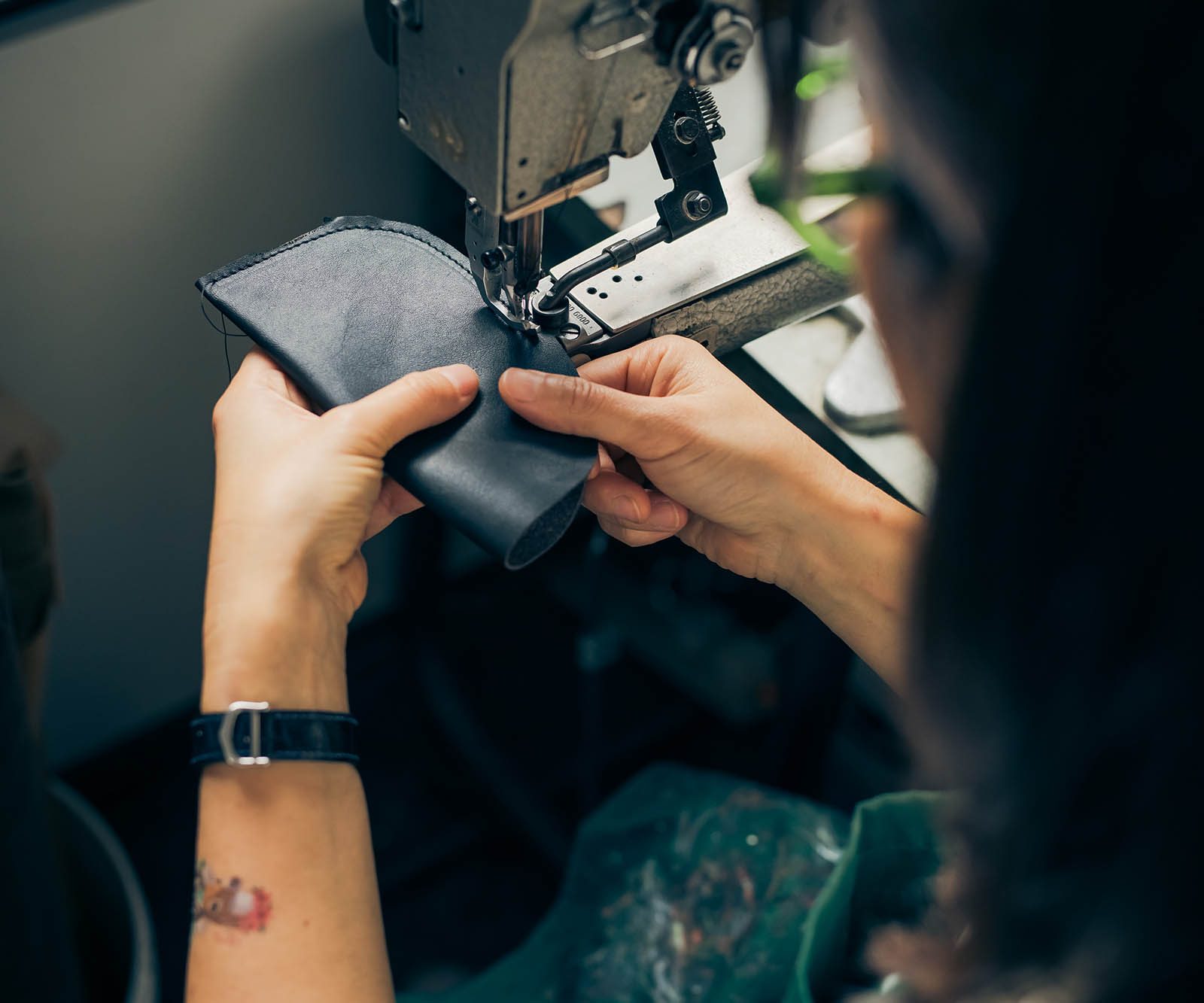 a woman sewing leather on a machine