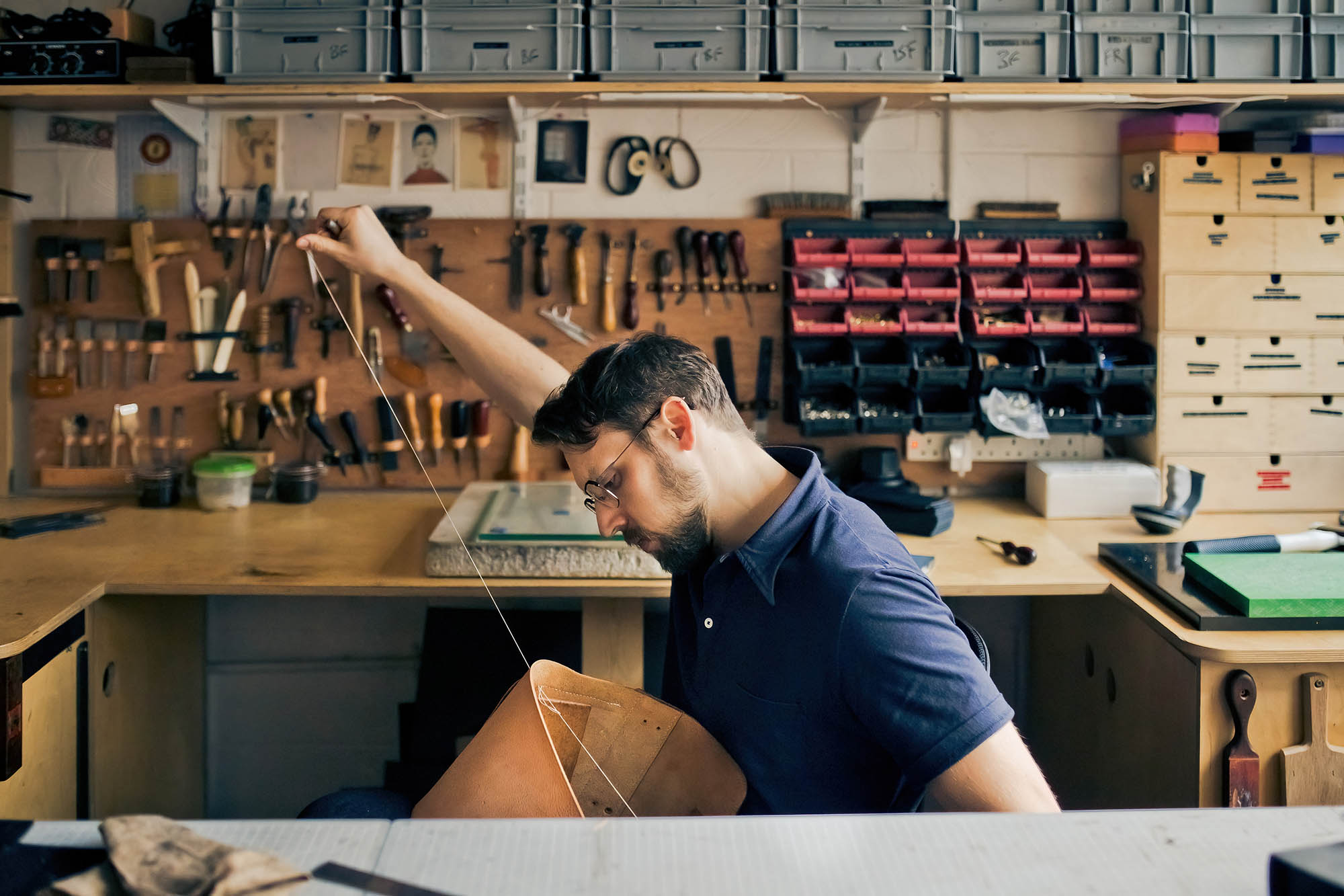 a leatherworker stitching in a workshop