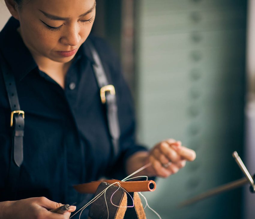 woman hand-stitching leather