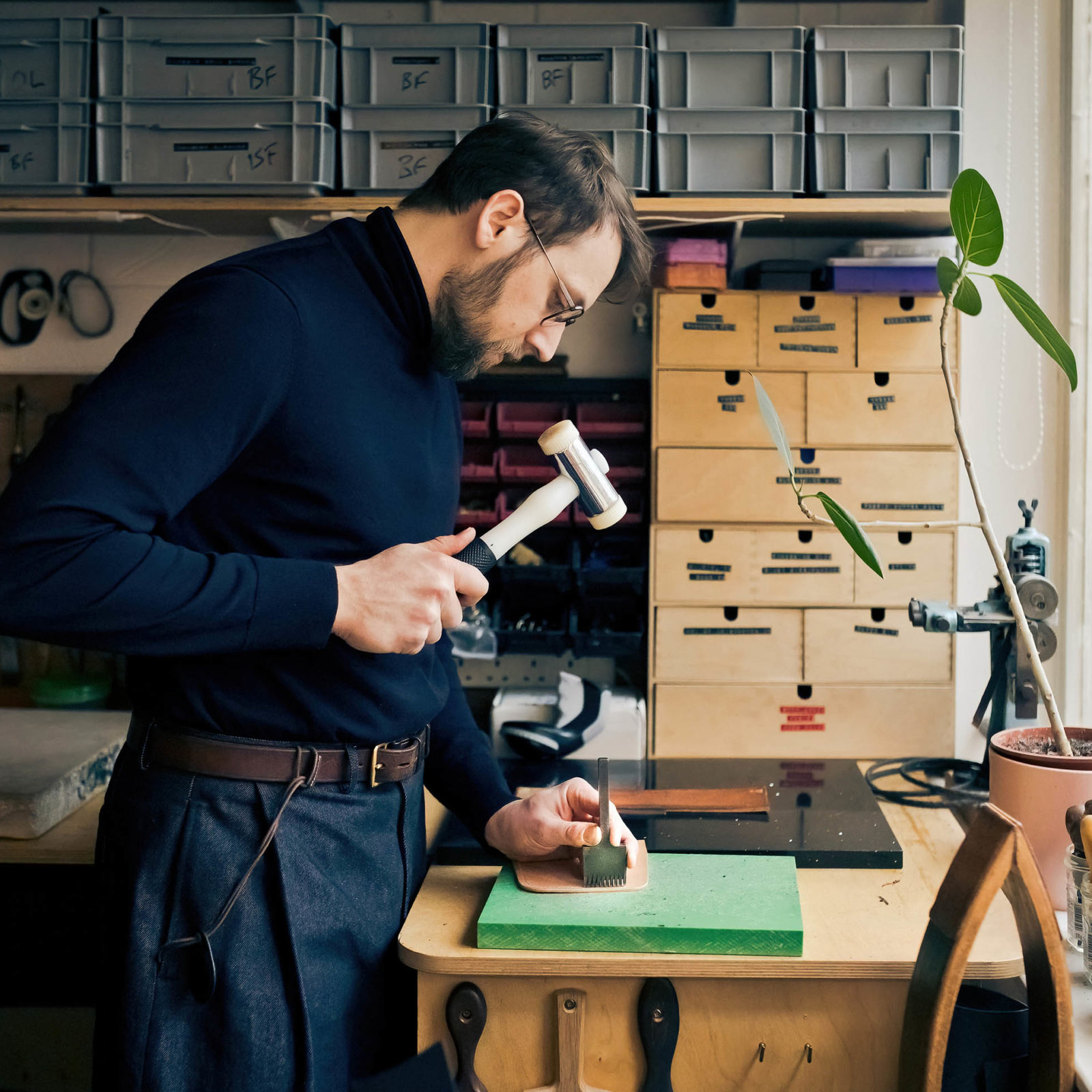 man using a hammer and other tools on leather