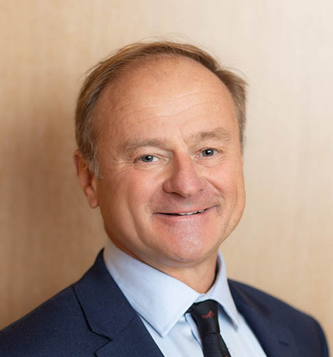 Portrait of a man wearing a blue shirt, navy jacket and tie