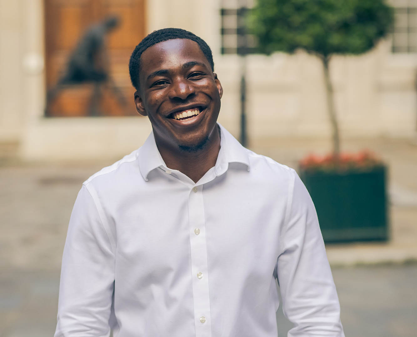 man in white shirt smiling on a cobbled street