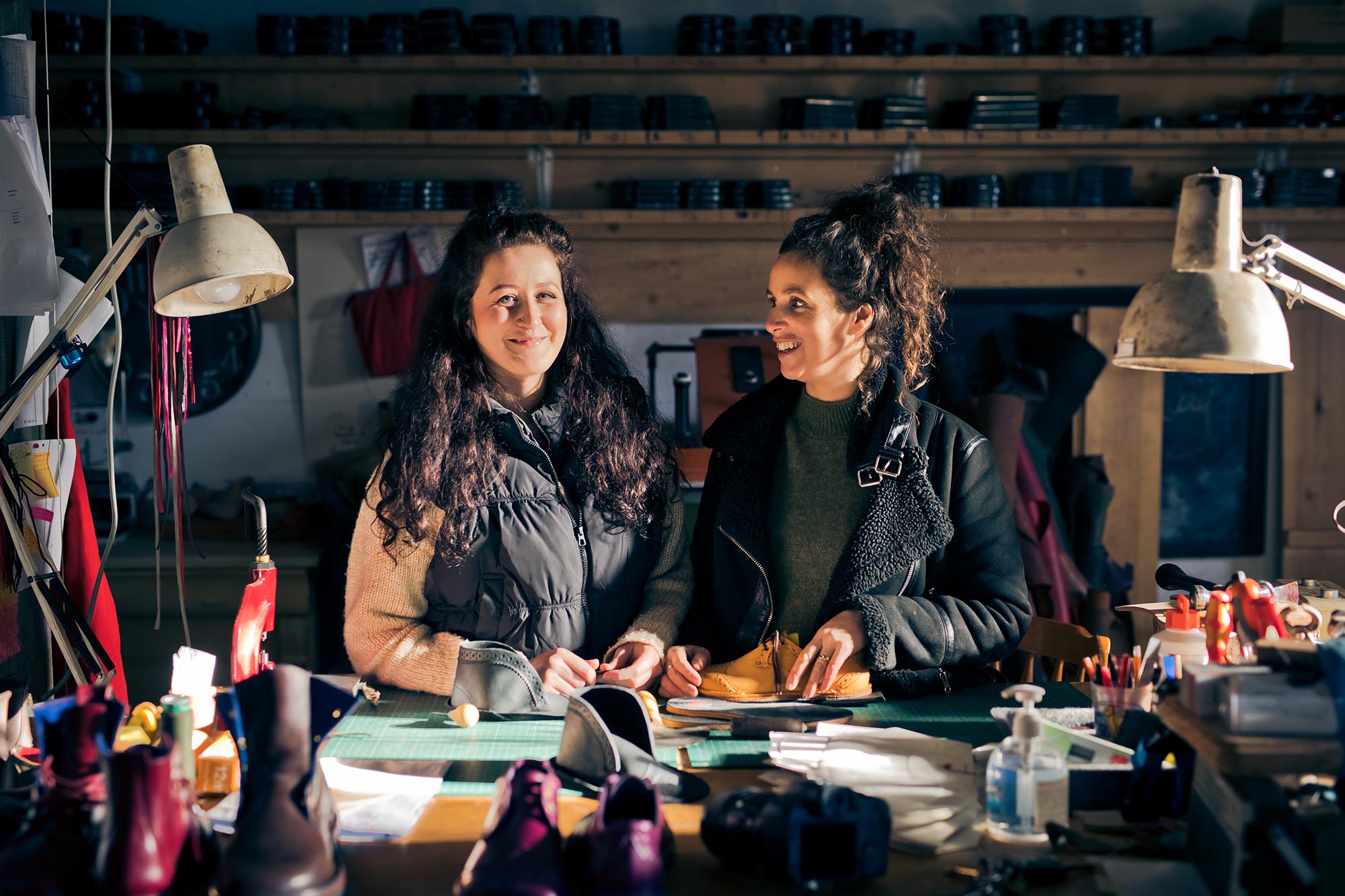 two women at a workbench with leather
