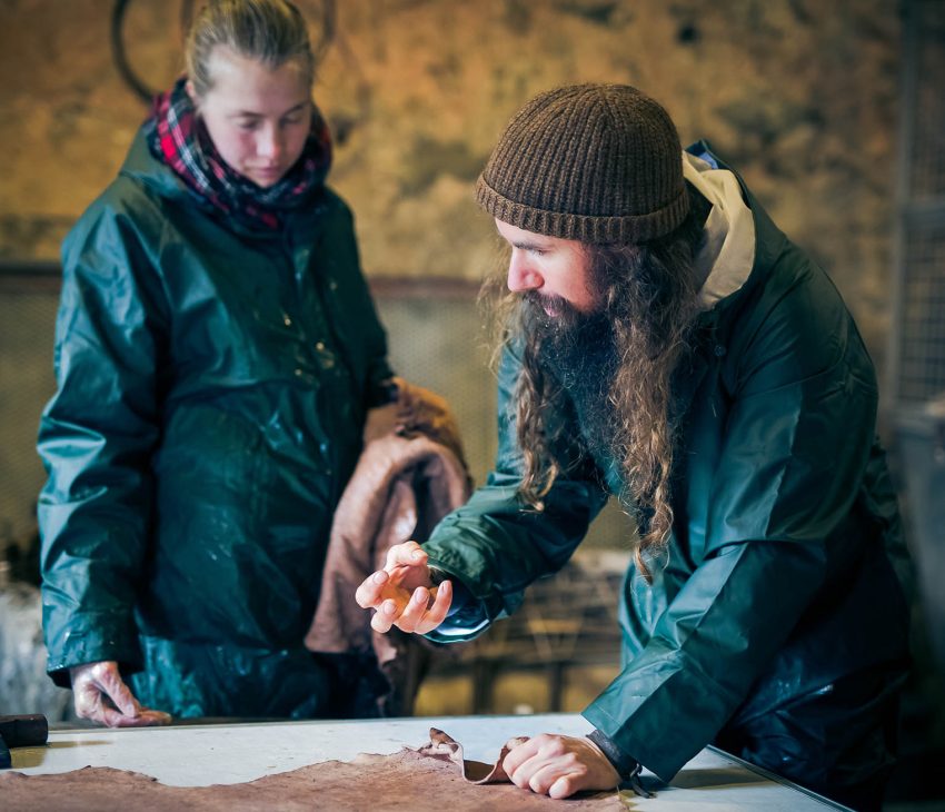 a woman and man working in a tannery dressed in green overalls