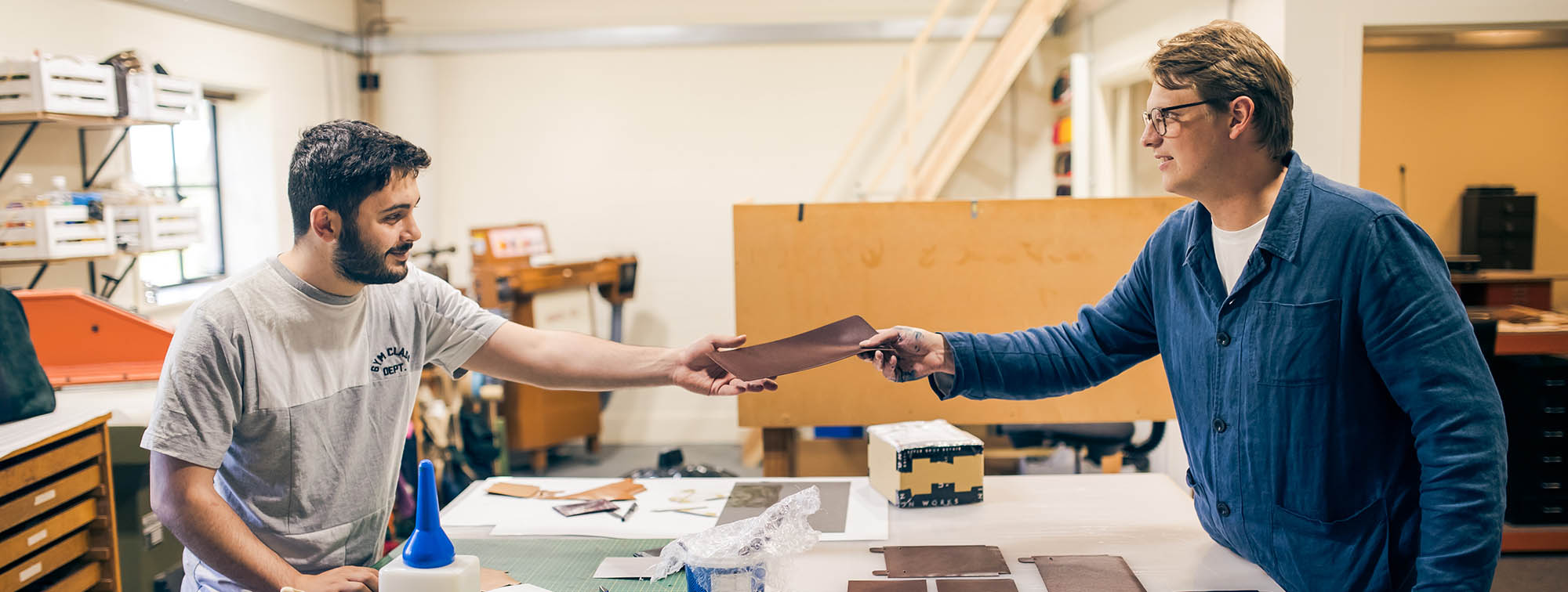 two men holding a piece of leather