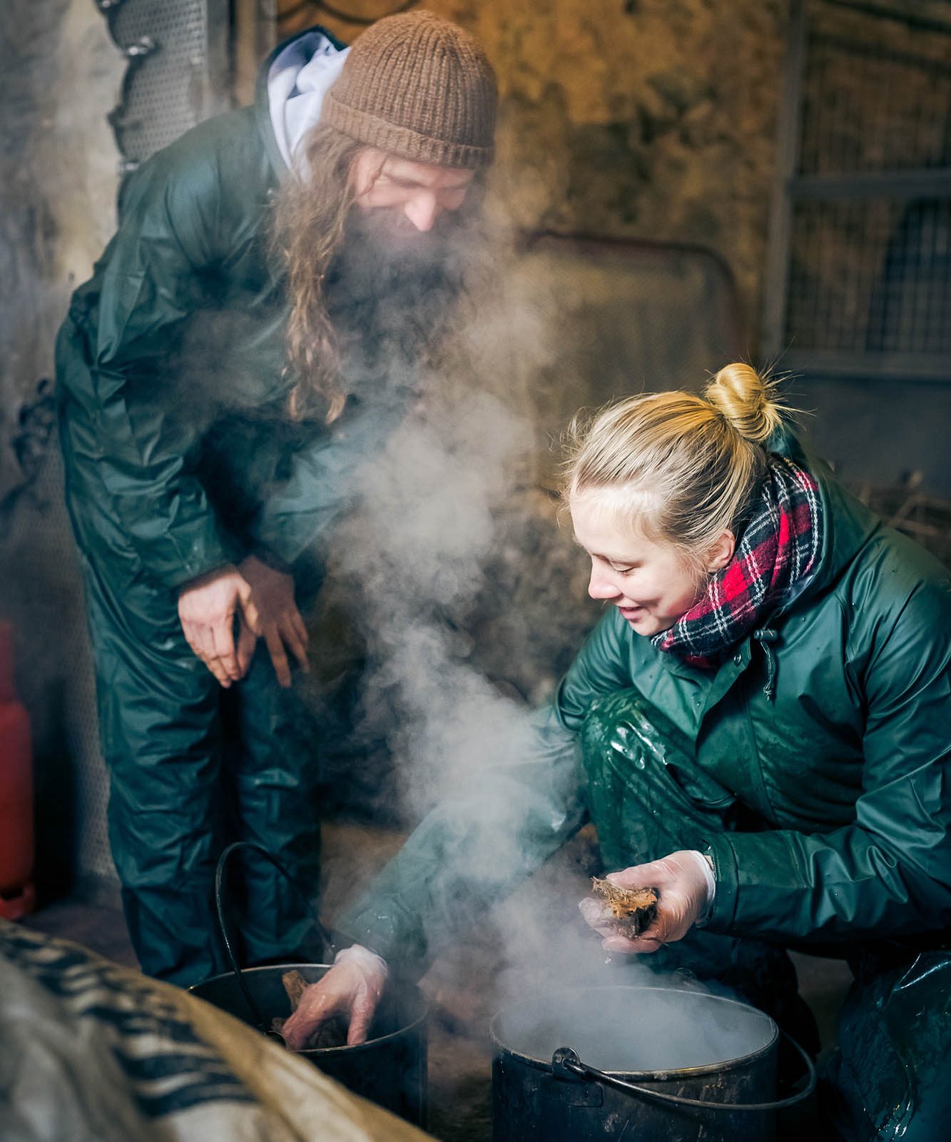 A man and a woman crouch over a smoking pot