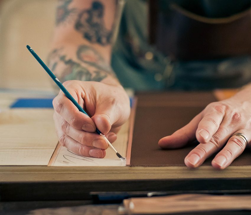 person using a paintbrush on leather and wood