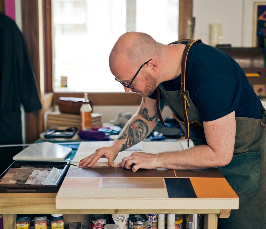 man making leather artwork in a studio