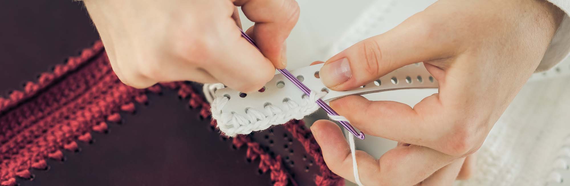 a woman's hands sewing thread through leather