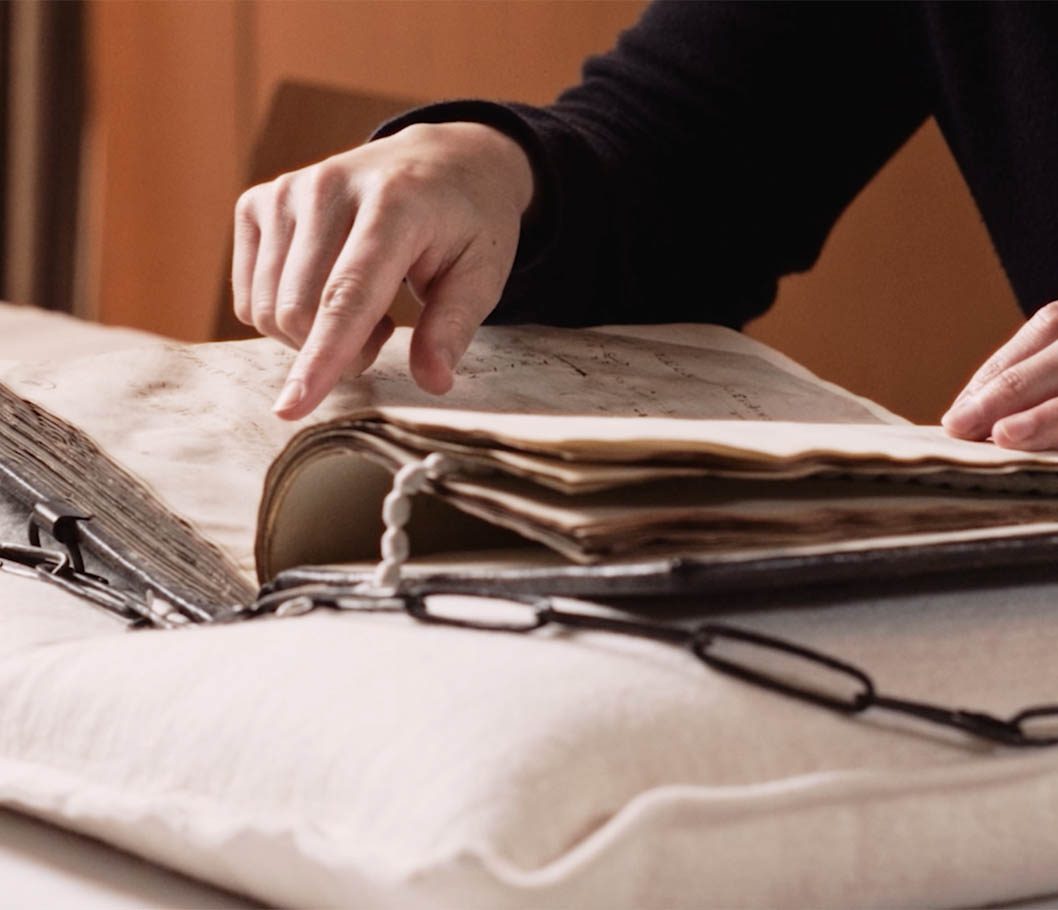 a hand pointing to a page of a medieval book
