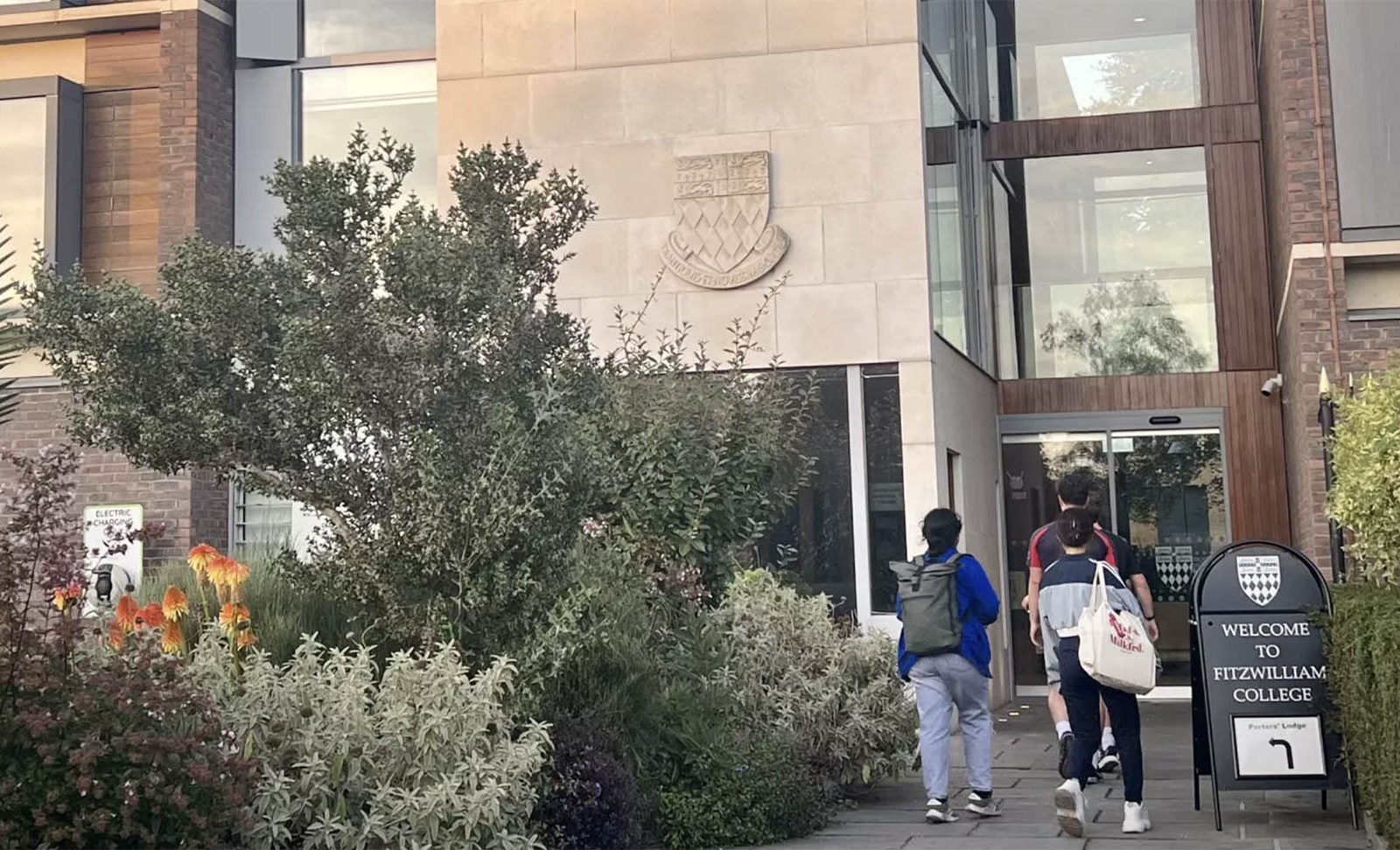 people entering a stone building with a garden in the foreground