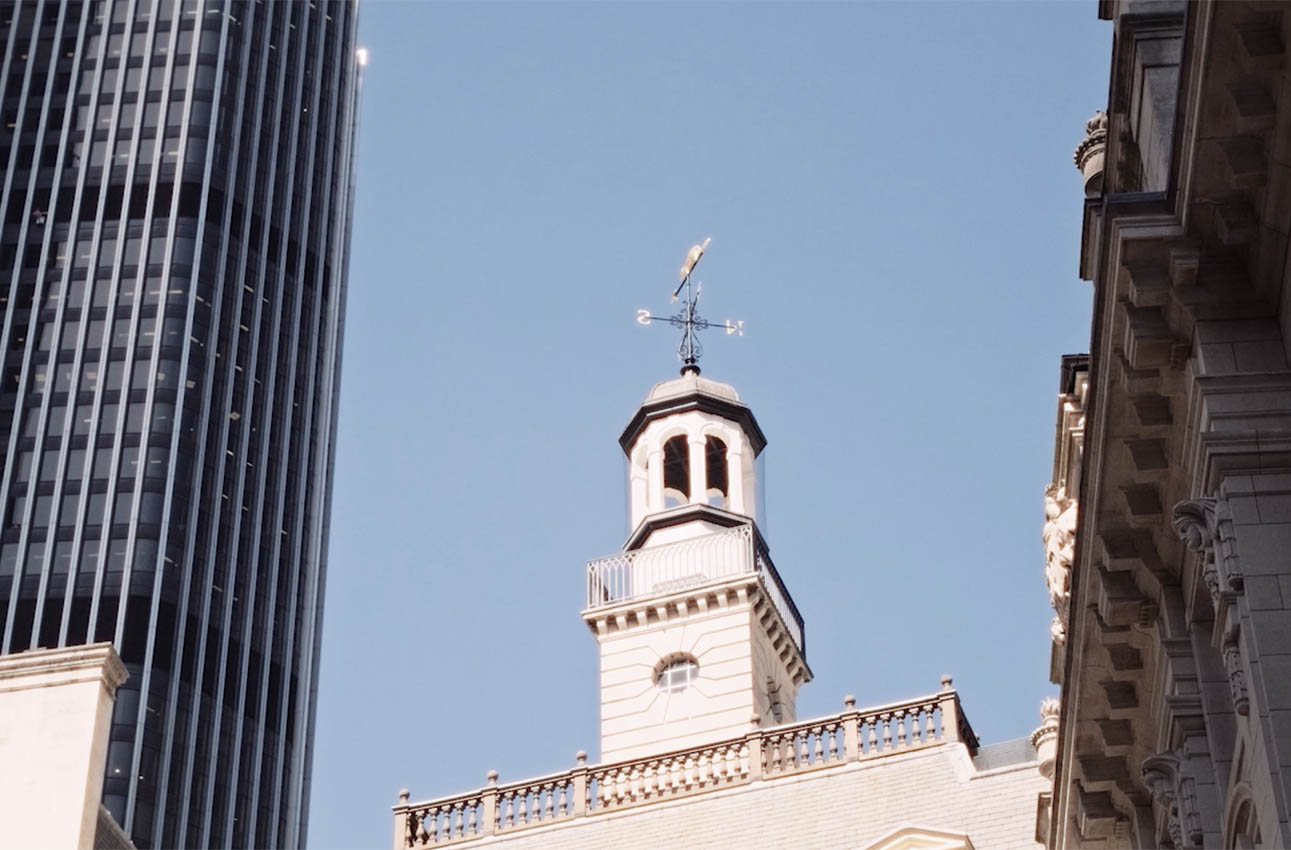 tall glass building in background with stone building in foreground
