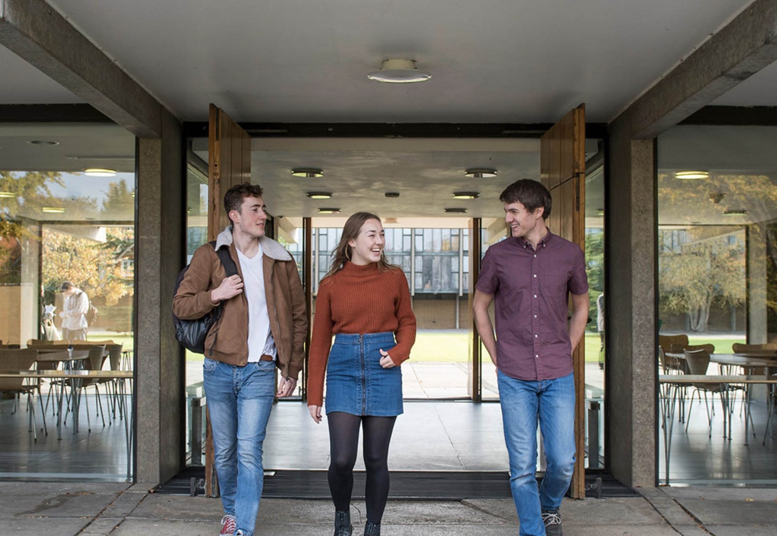 a girl and two boys exiting a glass building