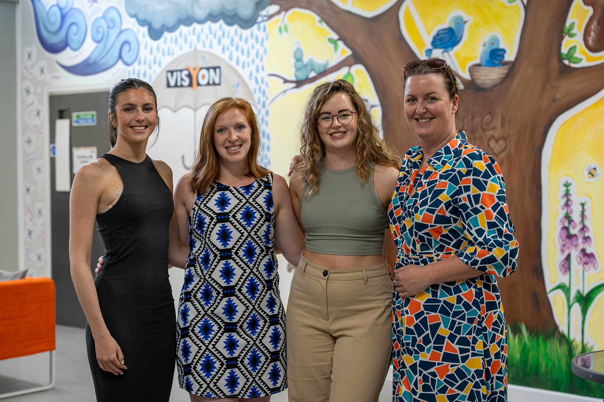a group of four women looking to camera smiling