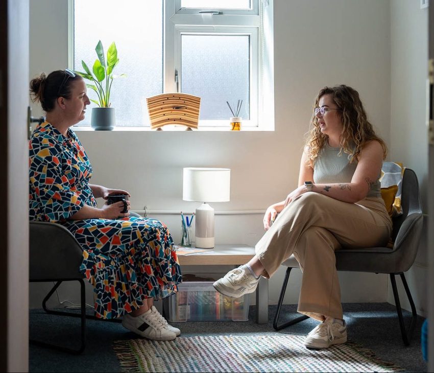 wwo women sitting in chairs opposite each other talking