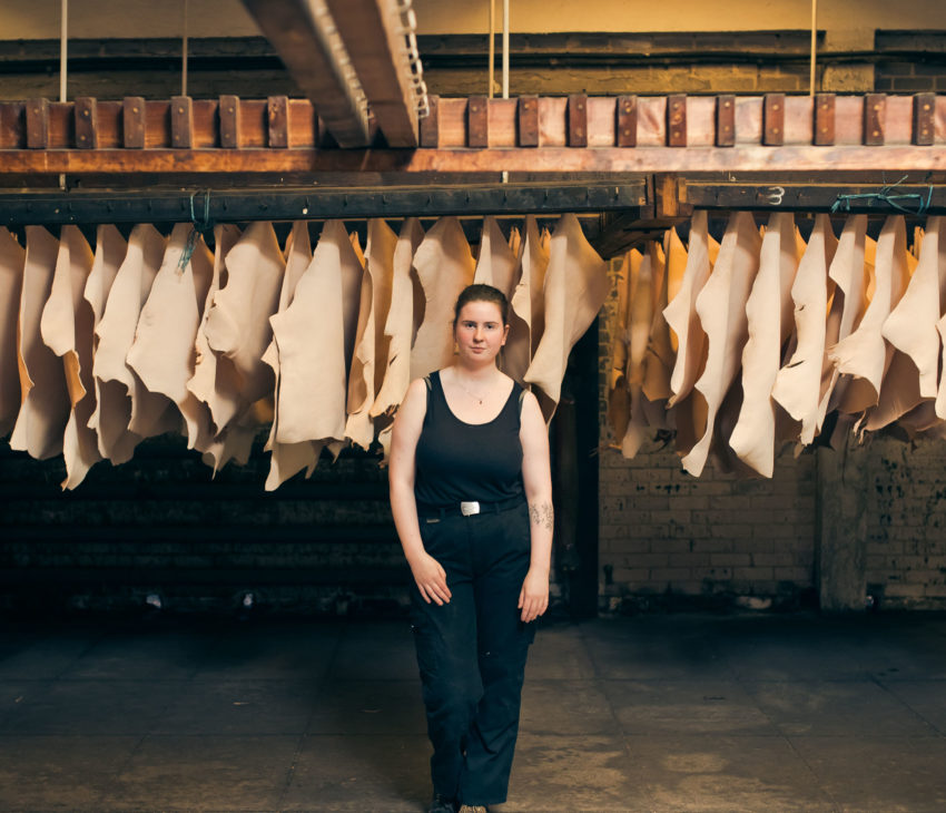 a girl dressed in black standing in front of tanned hides