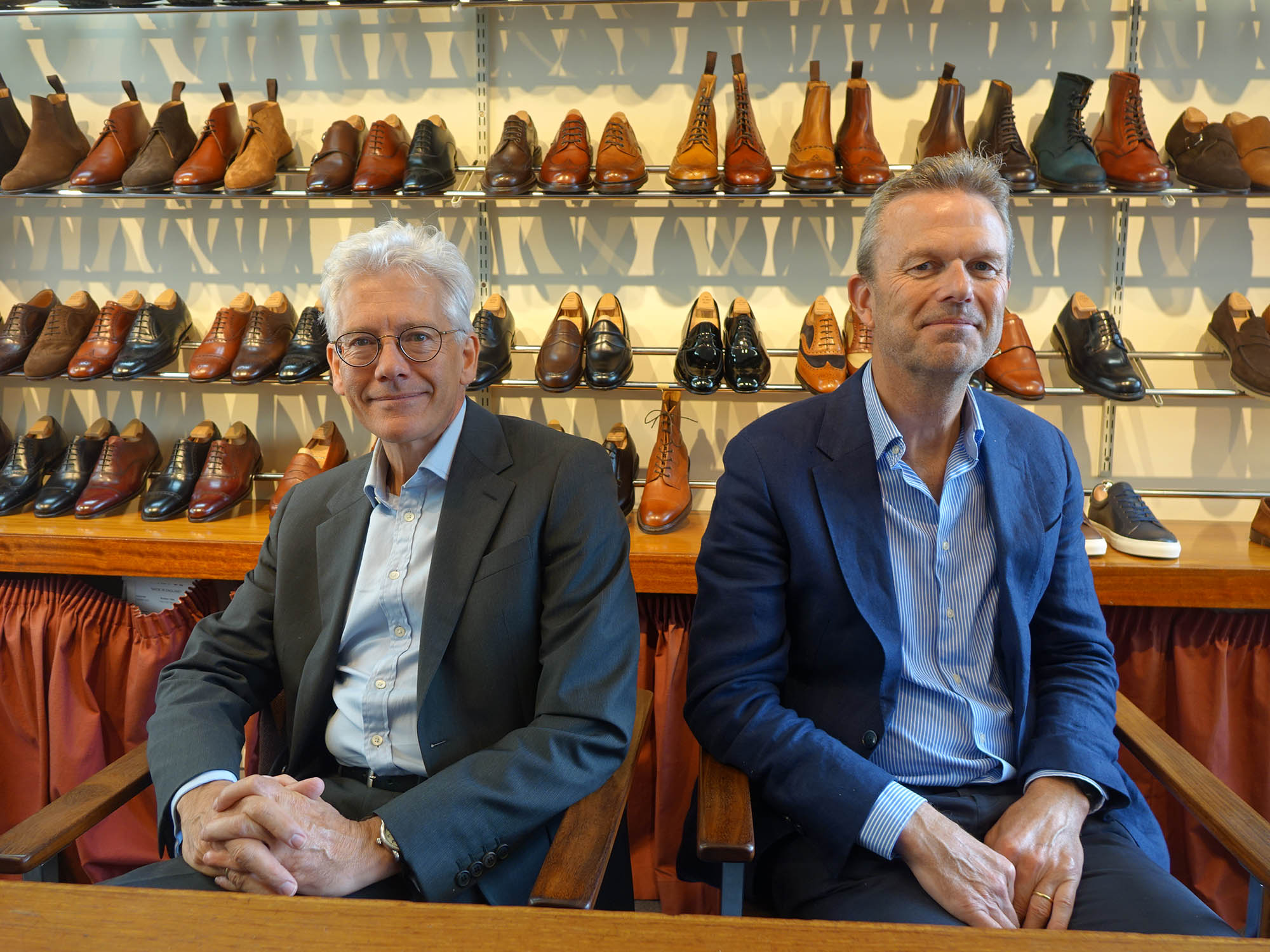 two men in suits with shoes behind them