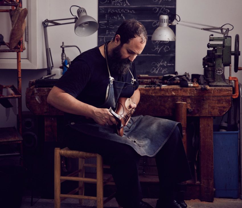 a man sitting on a chair making a shoe