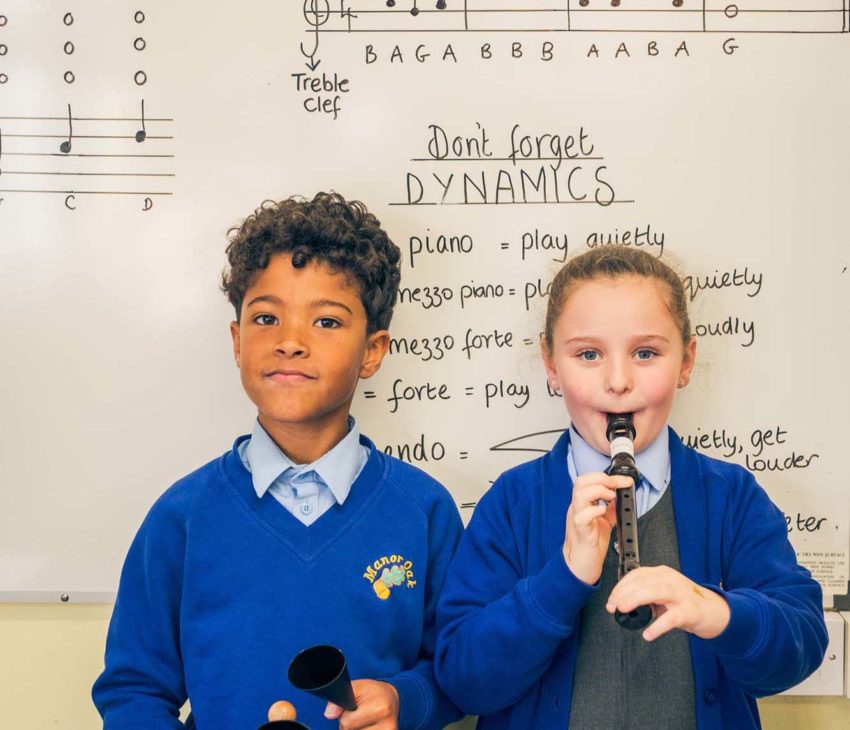 a boy and girl in front of whiteboard playing instruments