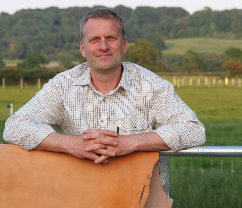 a man standing in a field with leather in the foreground