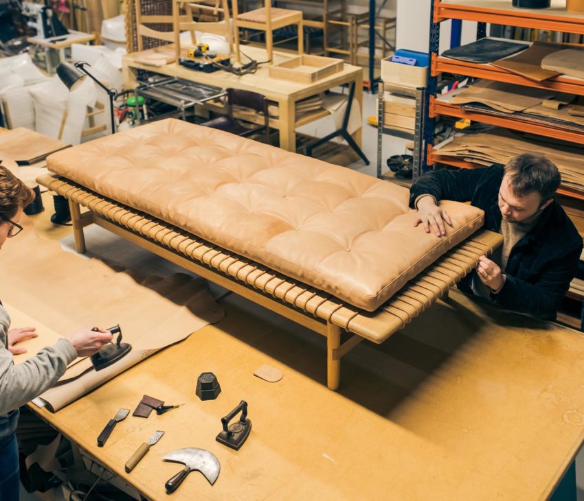 two men in a leatherworking studio with a leather sofa