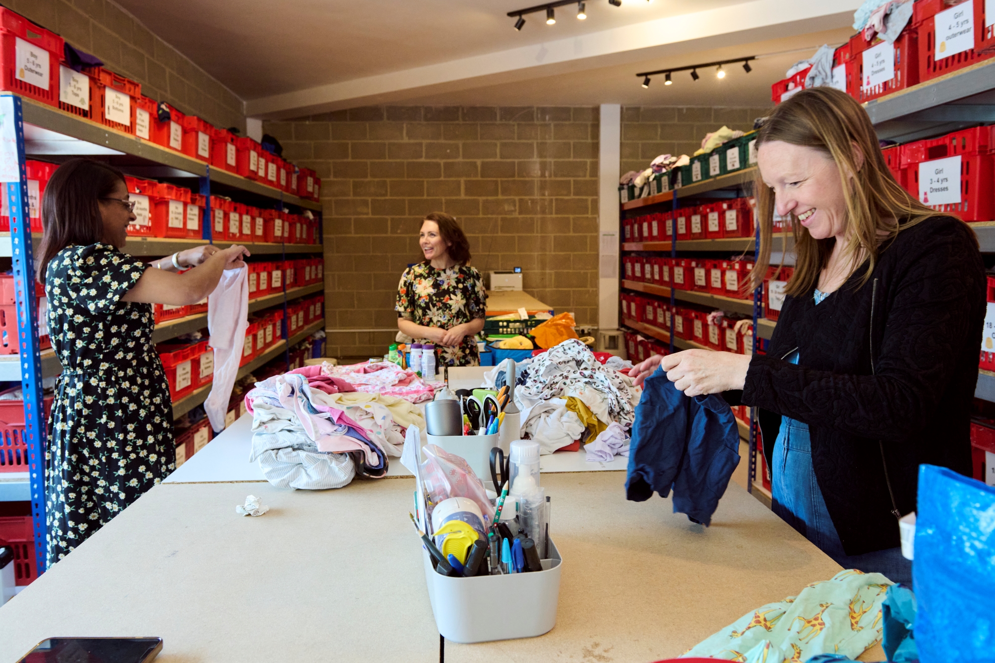 Three people sorting through baby cloths