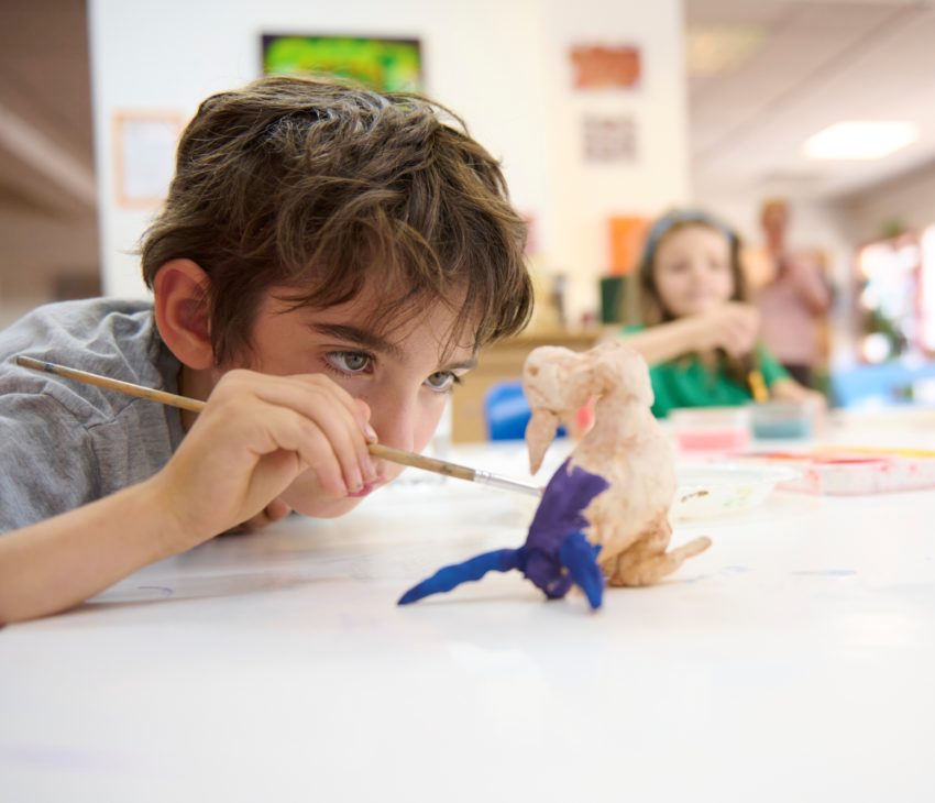 young boy paints model with purple paint