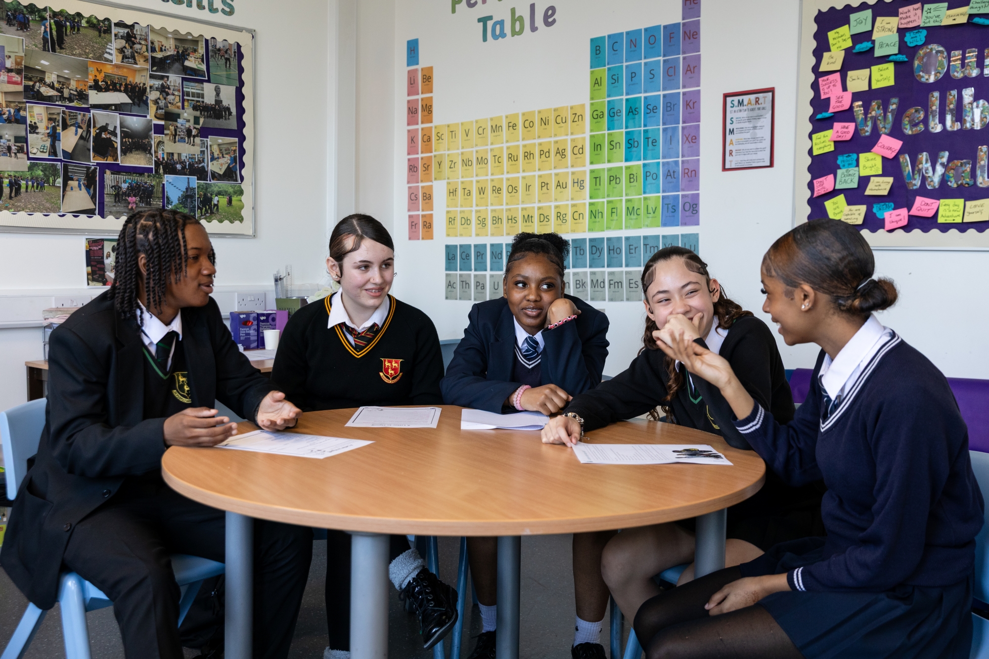 Students sit around a table talking.
