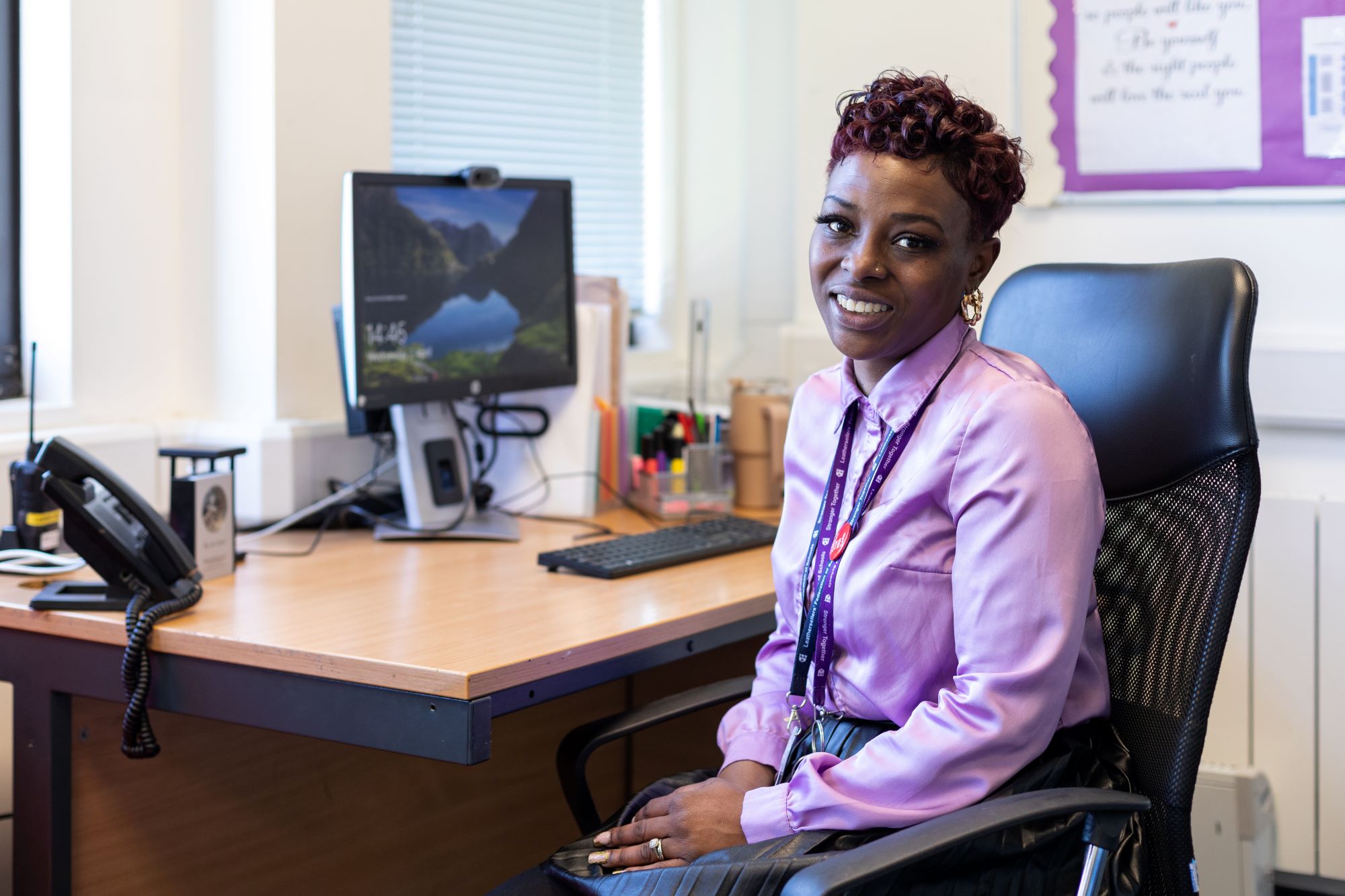 Women sits at desk looking into camera