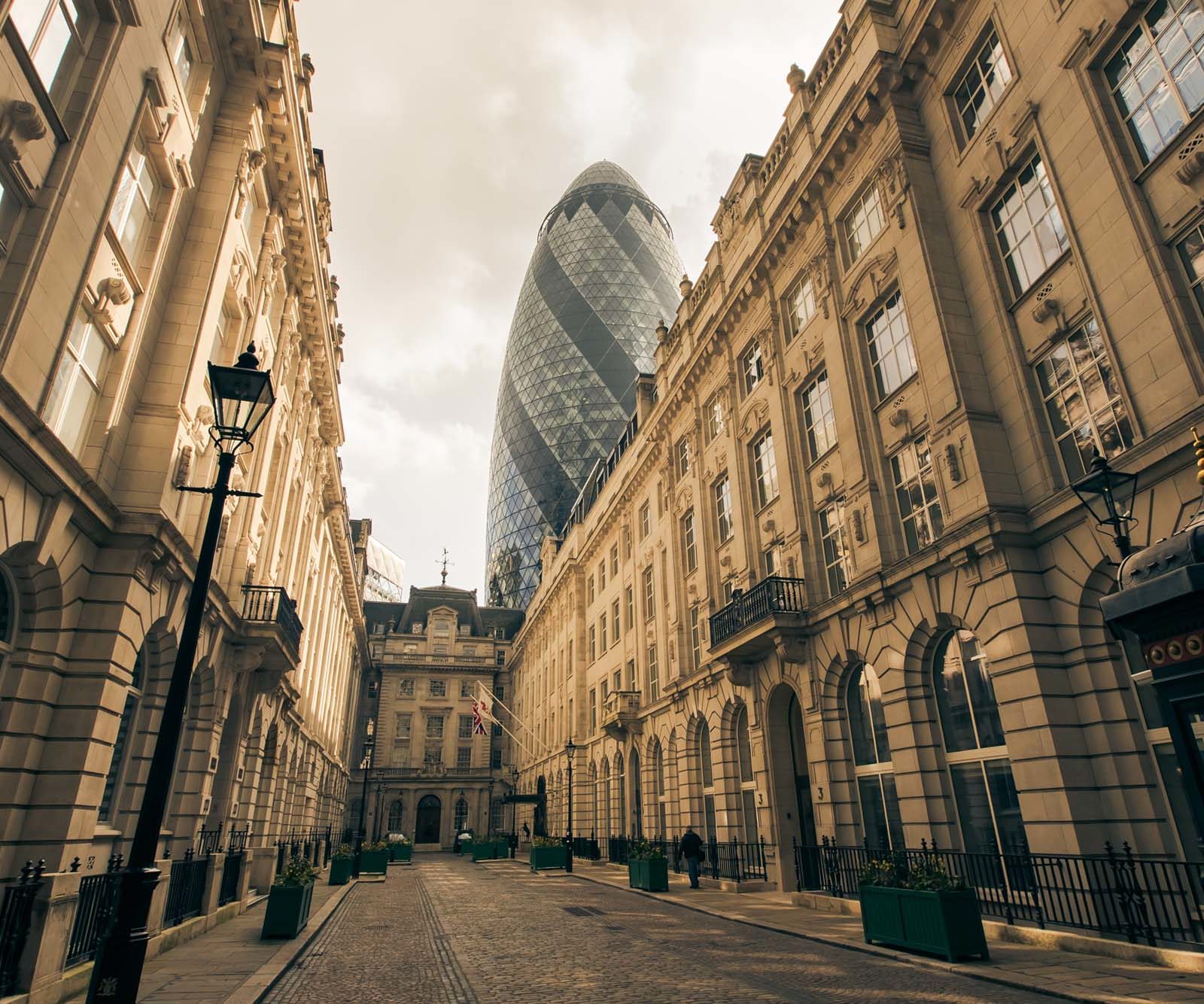 stone buildings and cobbled street with a glass tower in the background