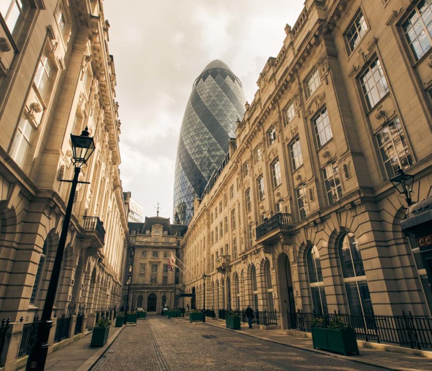 stone buildings and cobbled street with a glass tower in the background