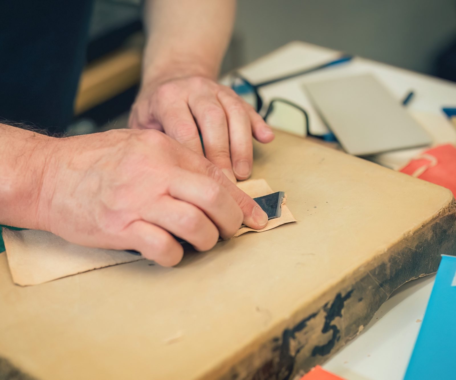 someone scraping the back off of a piece of leather