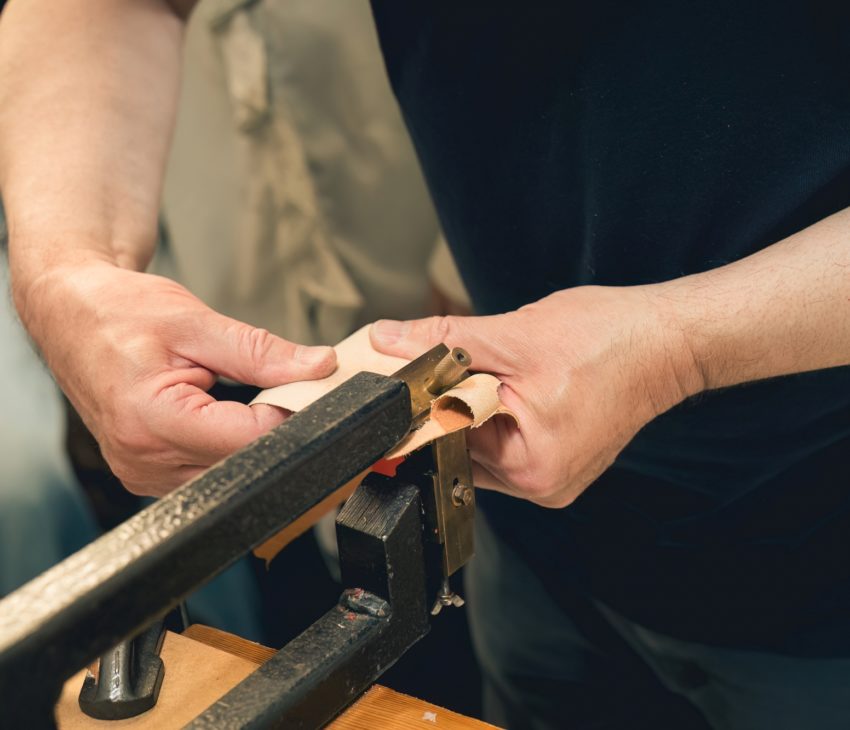 someone scraping the the back off of a piece of leather