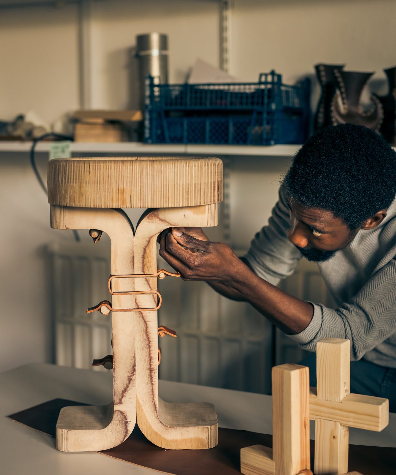 Student adjusting a stool made of wood and leather.