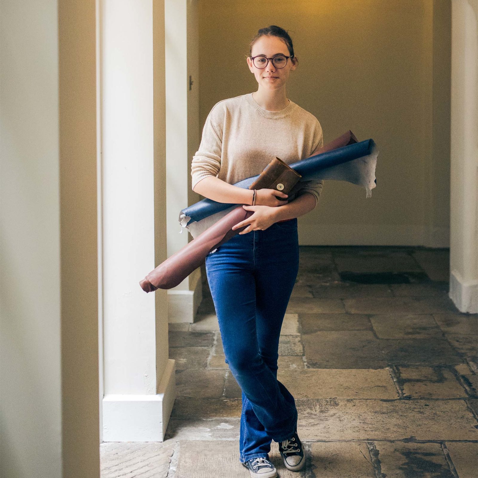woman standing on a stone floor holding leather hides